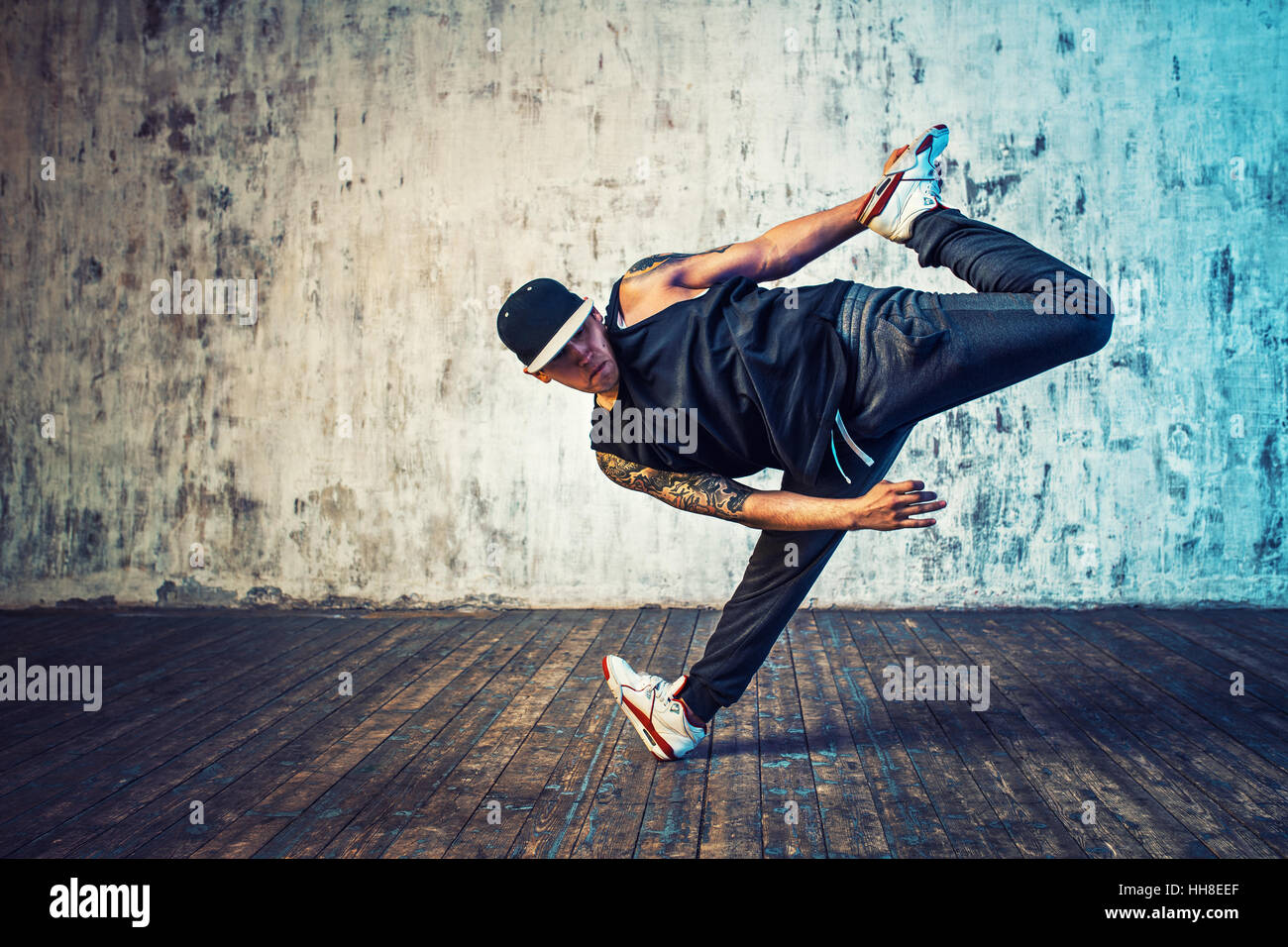 Junger Mann Breakdance auf Wand Hintergrund. Tattoo auf den Körper. Stockfoto
