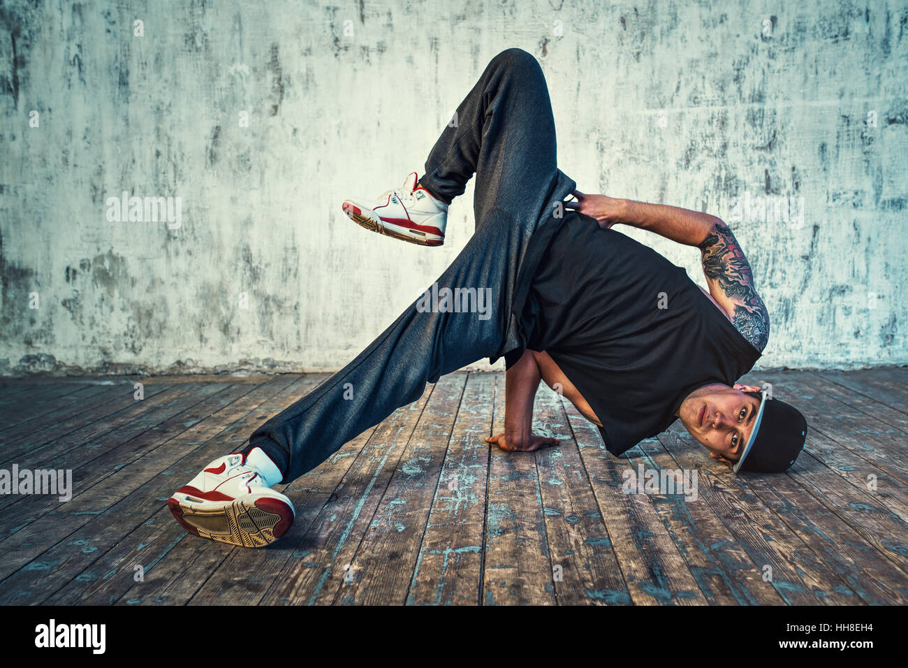 Junger Mann Breakdance auf Wand Hintergrund. Tattoo auf den Körper. Stockfoto