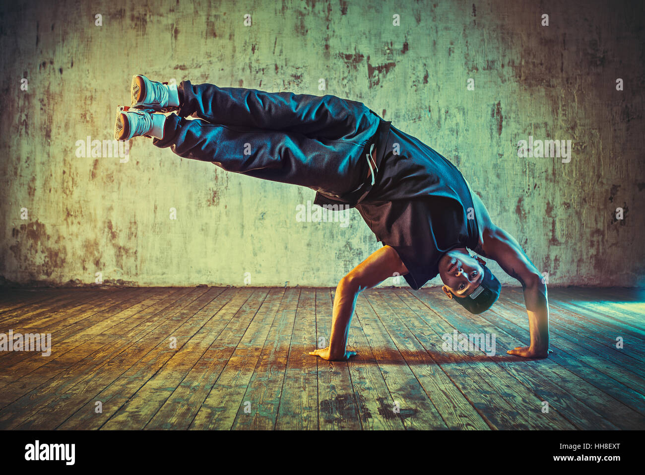 Junger Mann Breakdance auf Wand Hintergrund. Blau und gelb leuchtenden Farben Farbton. Stockfoto