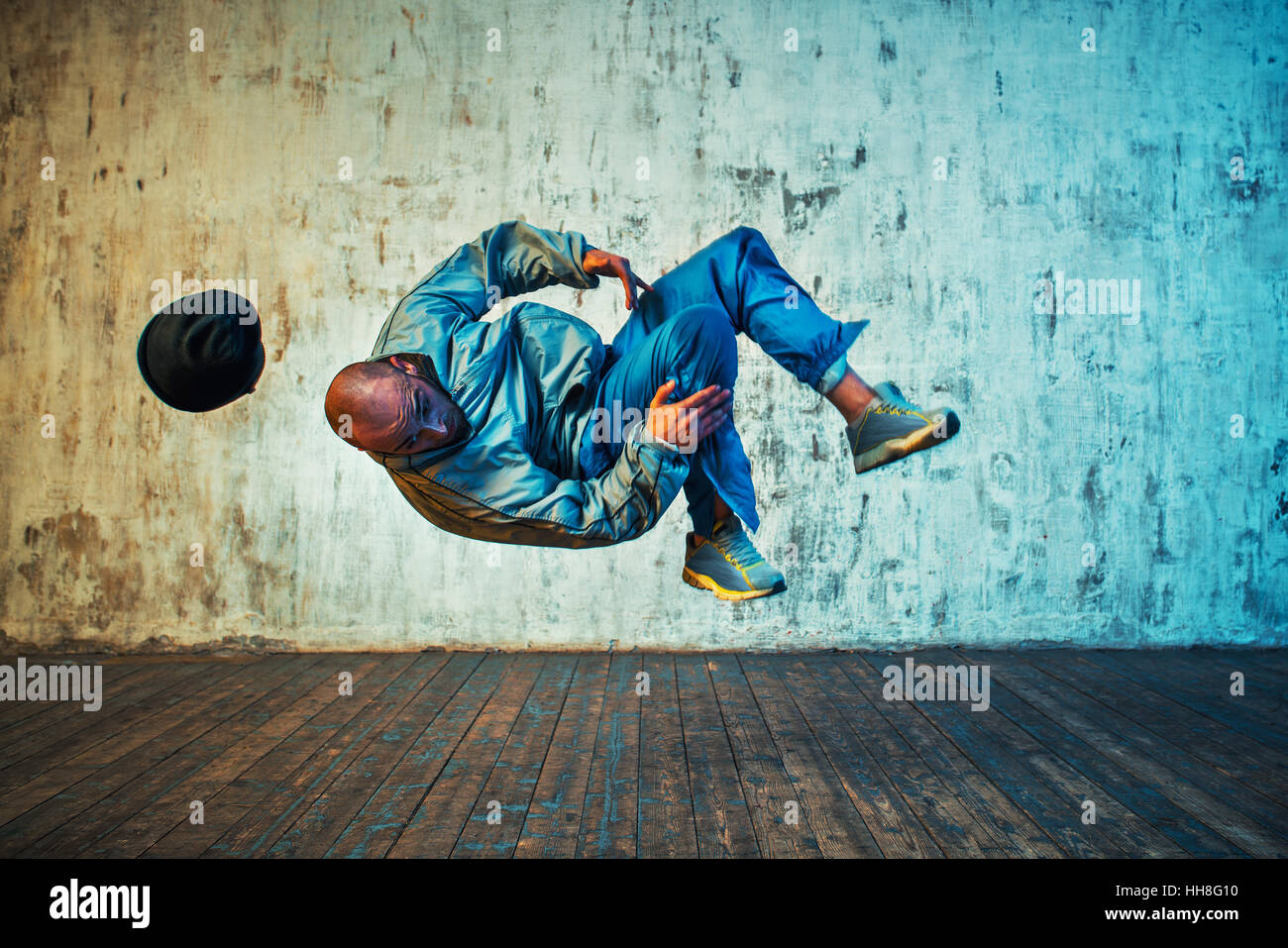 Junger Mann Breakdance auf Wand Hintergrund. Blättern Sie in der Luft. Stockfoto