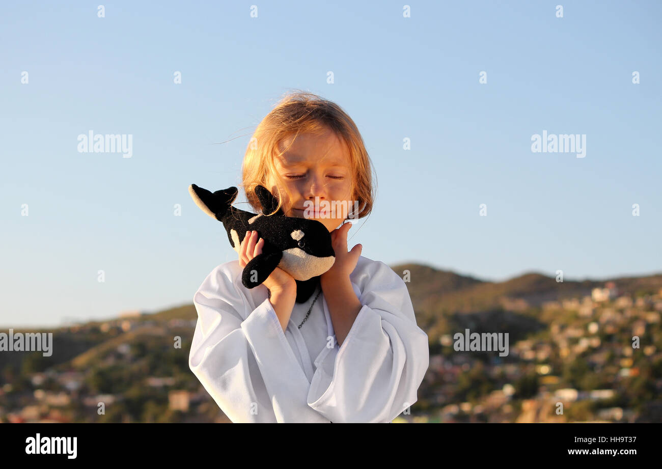 Verträumte Mädchen, geschlossenen Augen, Lächeln, mit Spielzeug Wal im Freien in der Sonne Stockfoto