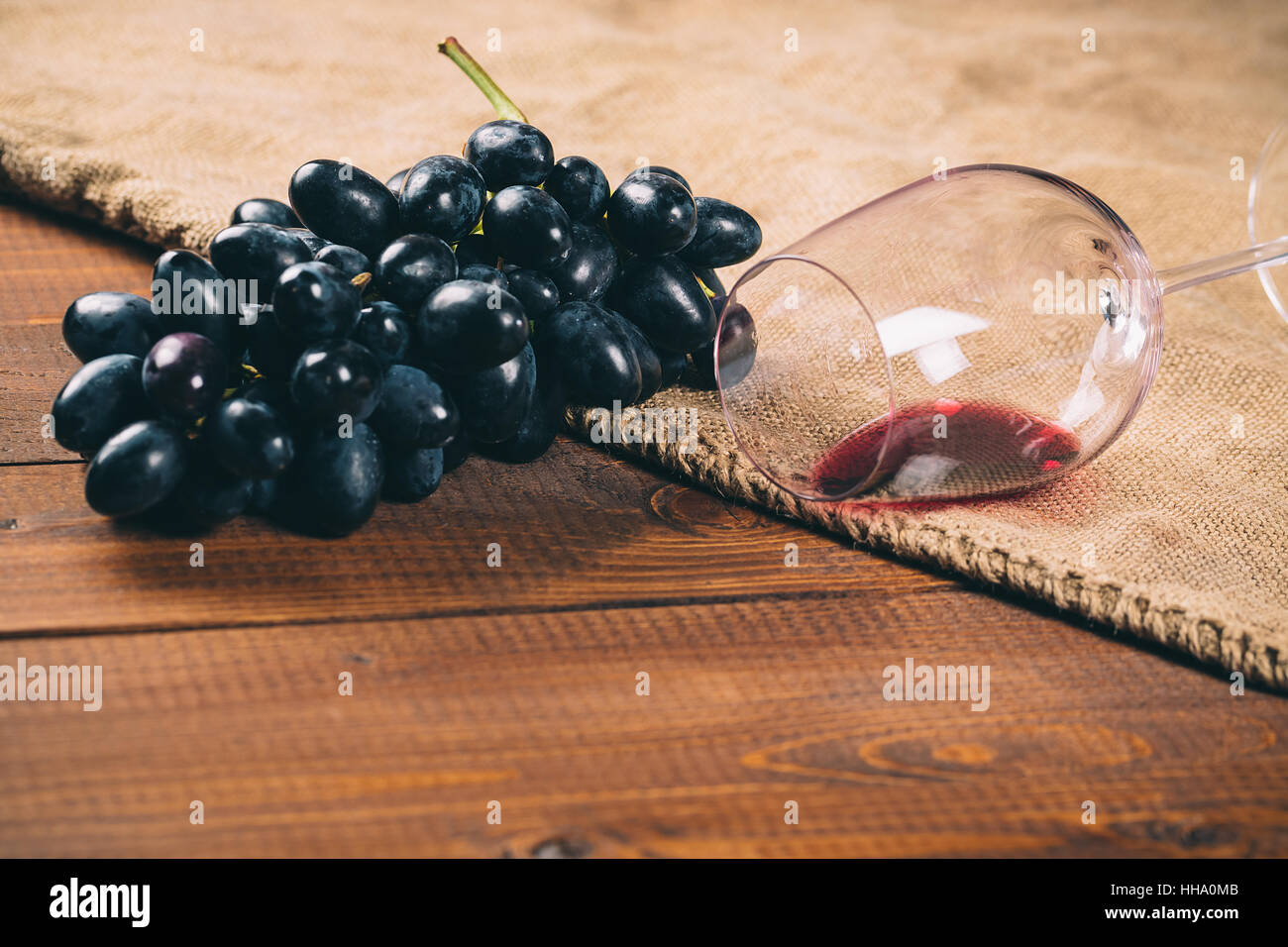 Glas Rotwein und Traubensaft auf hölzernen Hintergrund mit Sackleinen Stockfoto