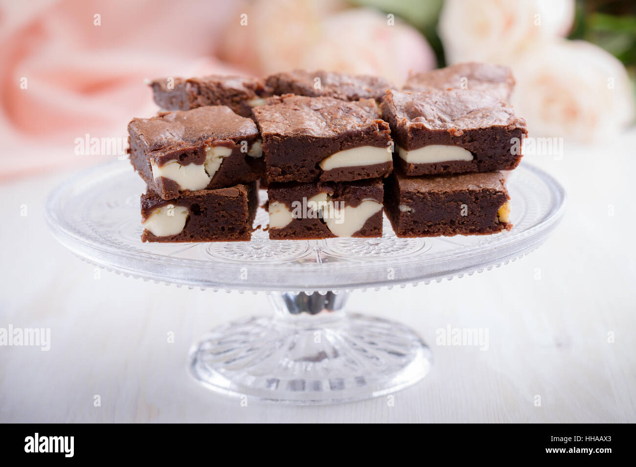Valentinstag-Käsekuchen-Brownies auf Kuchen stehen auf rosa Rosen Hintergrund Stockfoto
