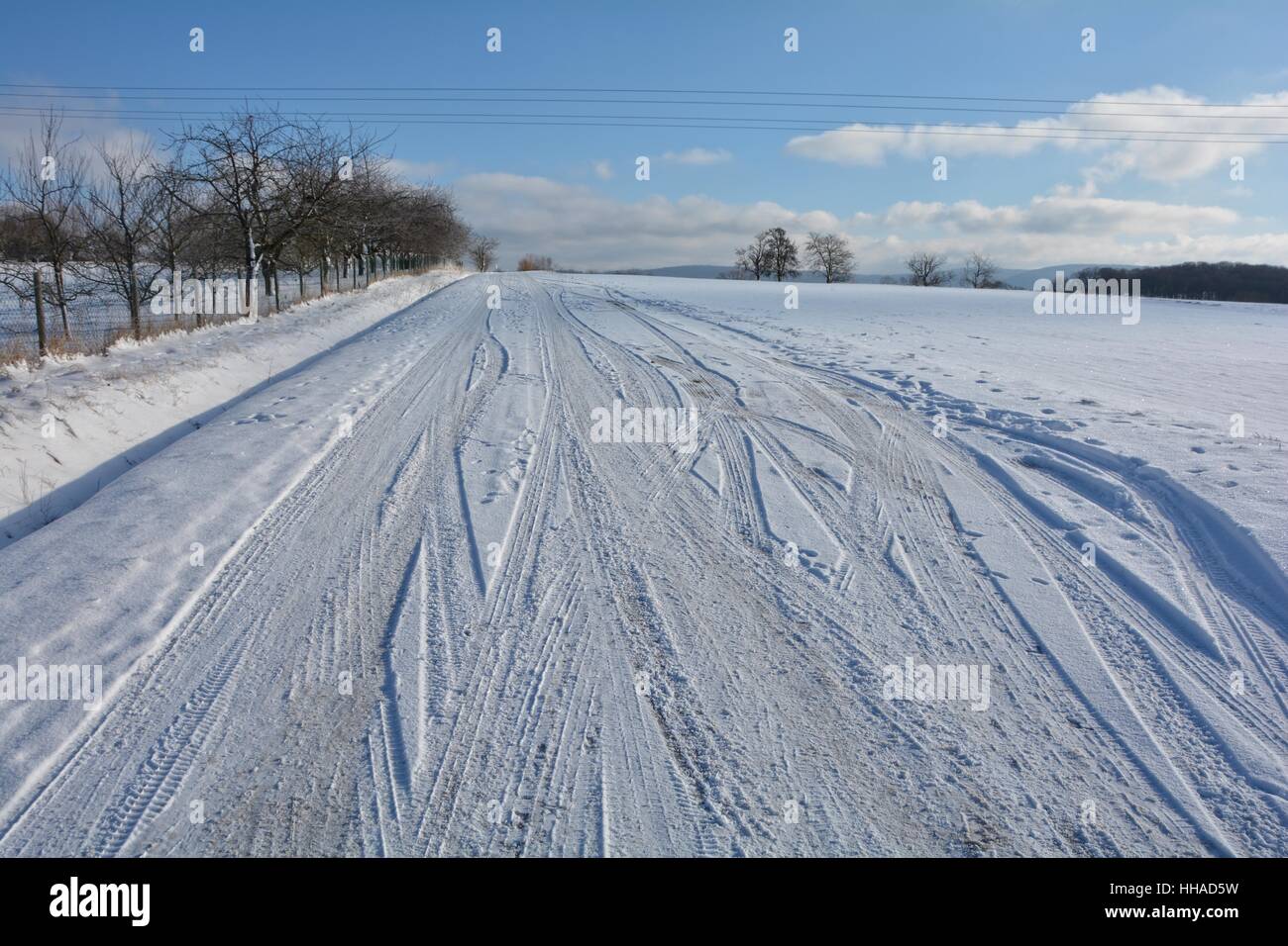 Schneebedeckte Straße in verschneite Landschaft mit vielen Reifen Spuren Stockfoto