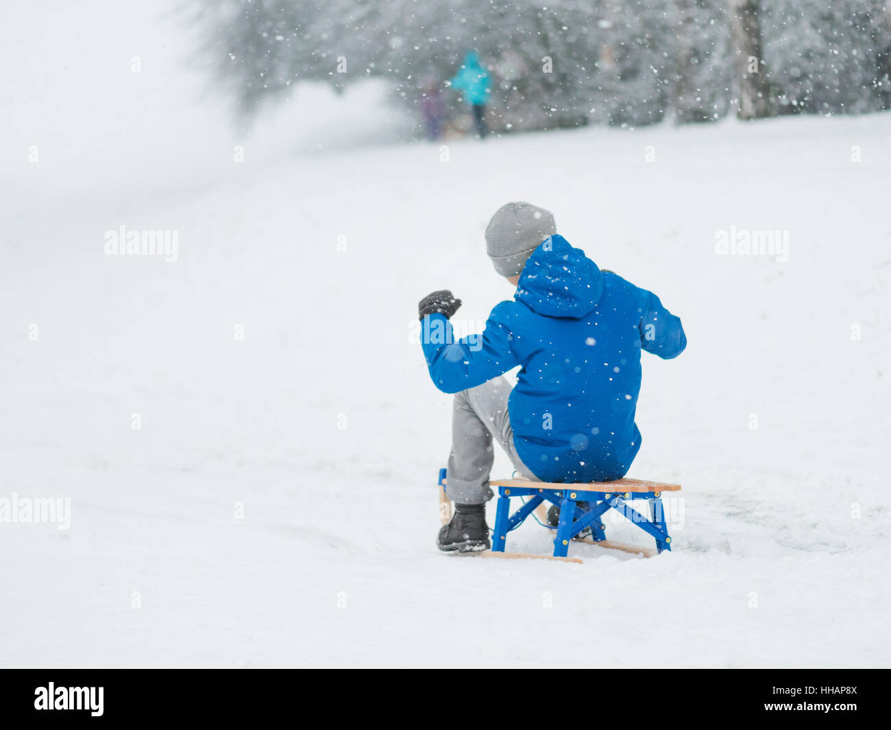 Kinder spielen im Schnee mit Schlitten Stockfoto