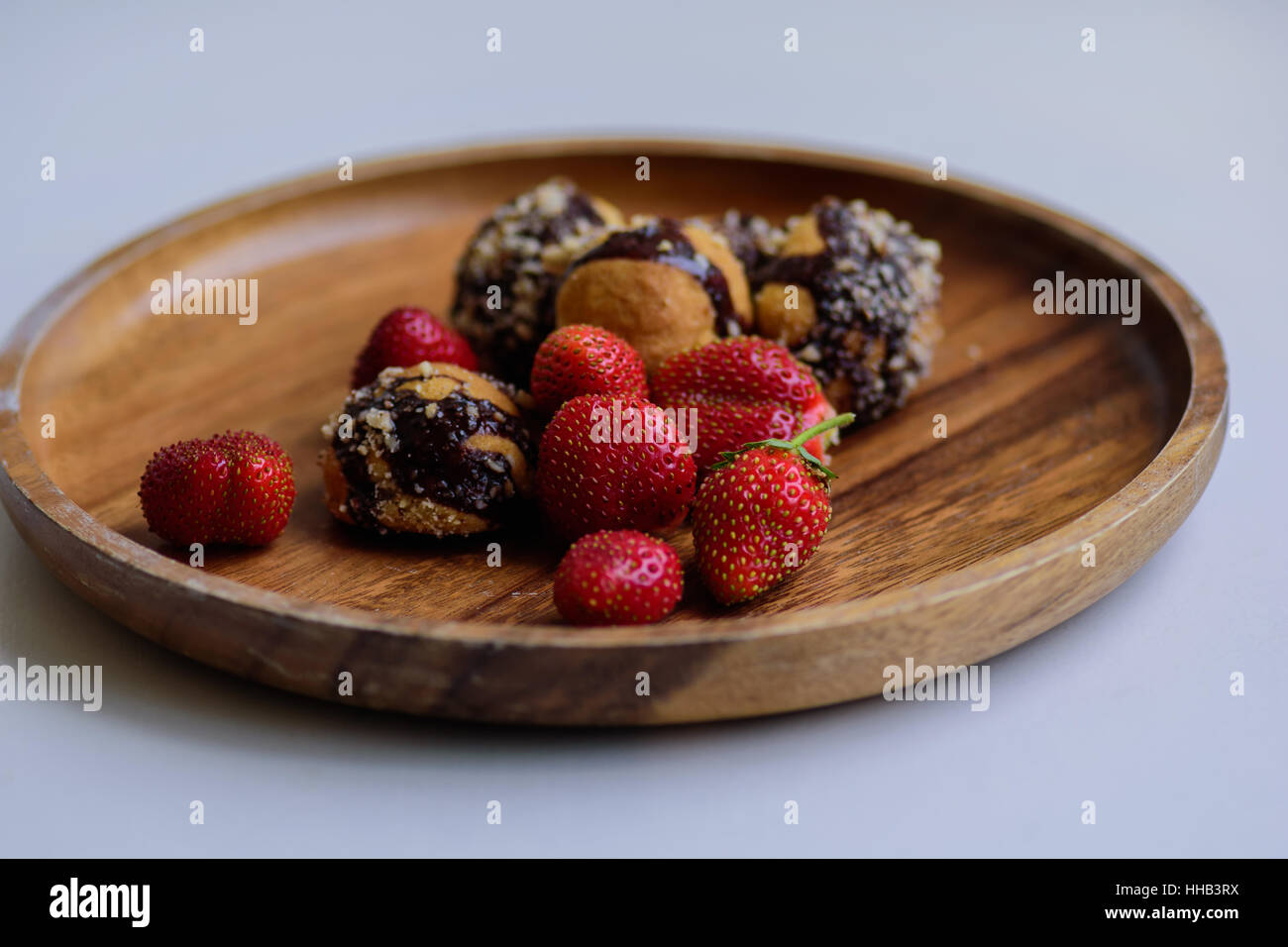 frisch geerntete reife Erdbeeren und hausgemachte Kekse serviert auf einer Holzplatte Stockfoto