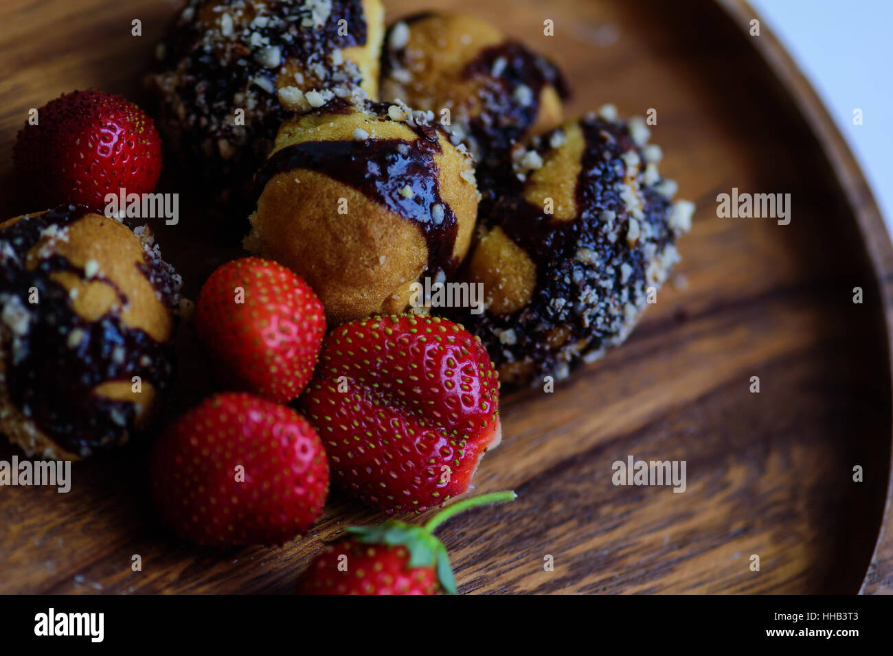 frisch geerntete reife Erdbeeren und hausgemachte Kekse serviert auf einer Holzplatte Stockfoto