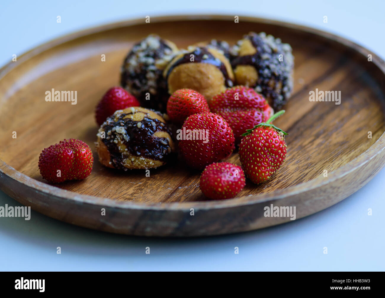 frisch geerntete reife Erdbeeren und hausgemachte Kekse serviert auf einer Holzplatte Stockfoto