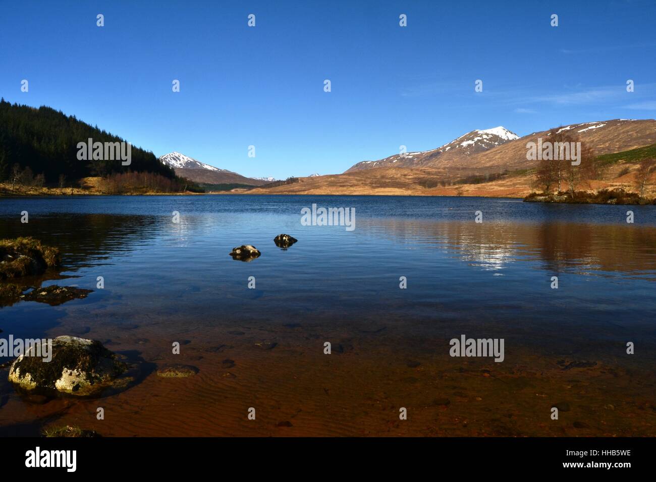 Poulary Loch an einem klaren, blauen Tag mit Gipfeln von Knoydart, Schottland in der Ferne Stockfoto