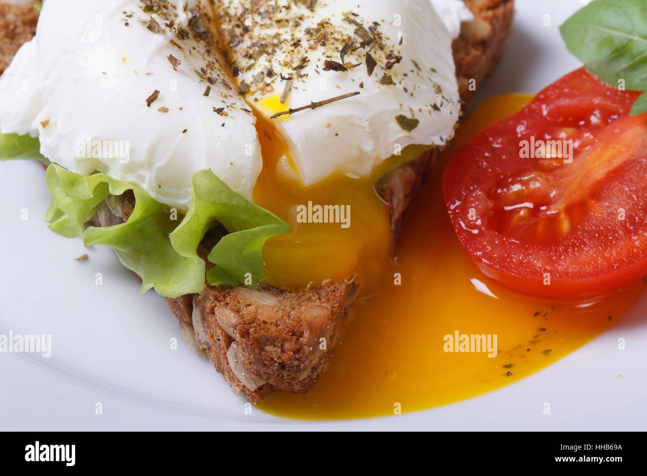 Eggs Benedict mit Brot und Tomaten auf einem Teller schließen sich horizontal Stockfoto