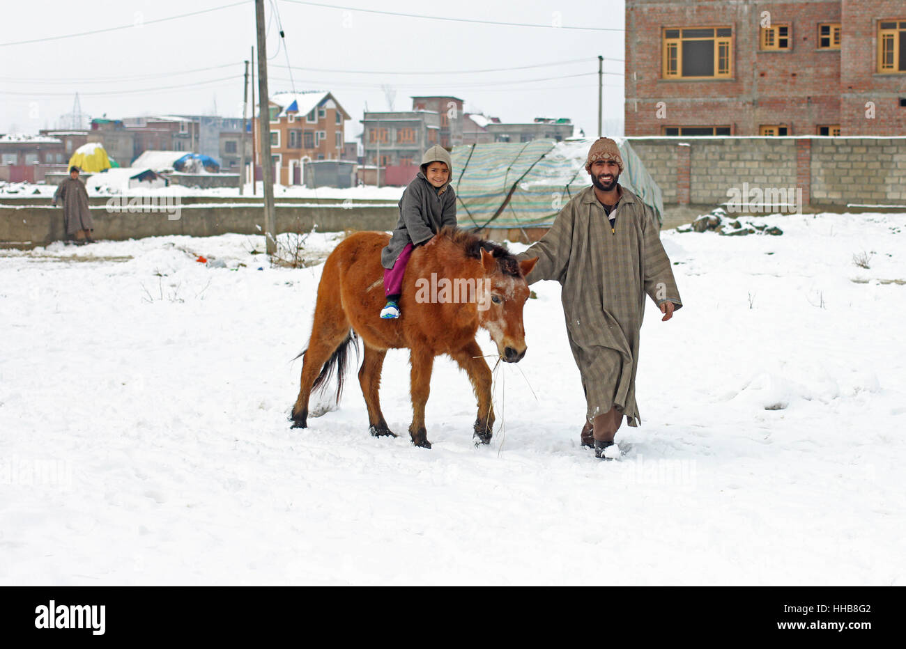 Srinagar, Indien. 18. Januar 2017. Ein Nomade unter seiner Tochter für ein Pferd Reiten inmitten von Schneefall und Knochen kühlen Kälte in Indien kontrollierten Kaschmir Hauptstadt-Srinagar. Wetterfrösche haben mehr Schnee nächste Woche vorausgesagt. Bildnachweis: Umer Asif/Pacific Press/Alamy Live-Nachrichten Stockfoto