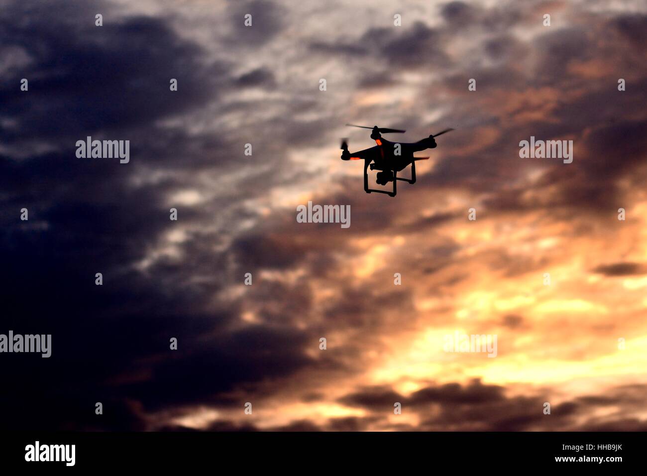 Die Drohne hebt ab, als die Sonne untergeht, so dass dem Bild eine leuchtende Orange mit dunklen Wolken, die Verbesserung der es fiel. Stockfoto