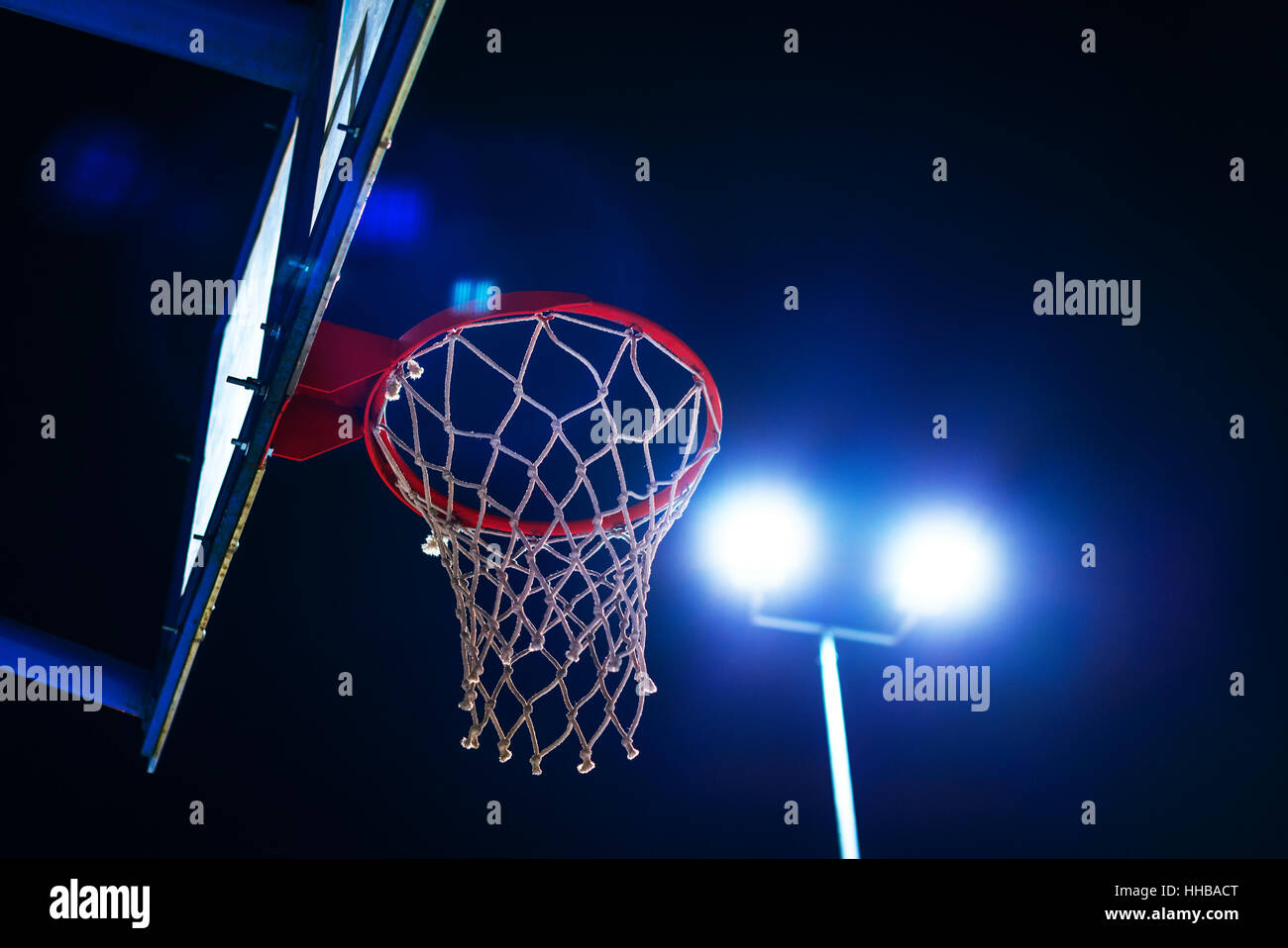 Flare-Basketballkorb auf Outdoor-Sportplatz in der Nacht mit Objektiv Stockfoto