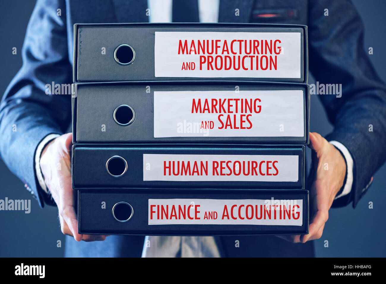 Geschäftsmann halten Sie Dokument Bindemittel mit vier wichtigen Geschäftsfunktionen - Produktion, marketing, Vertrieb, Personalwesen, accounti Stockfoto
