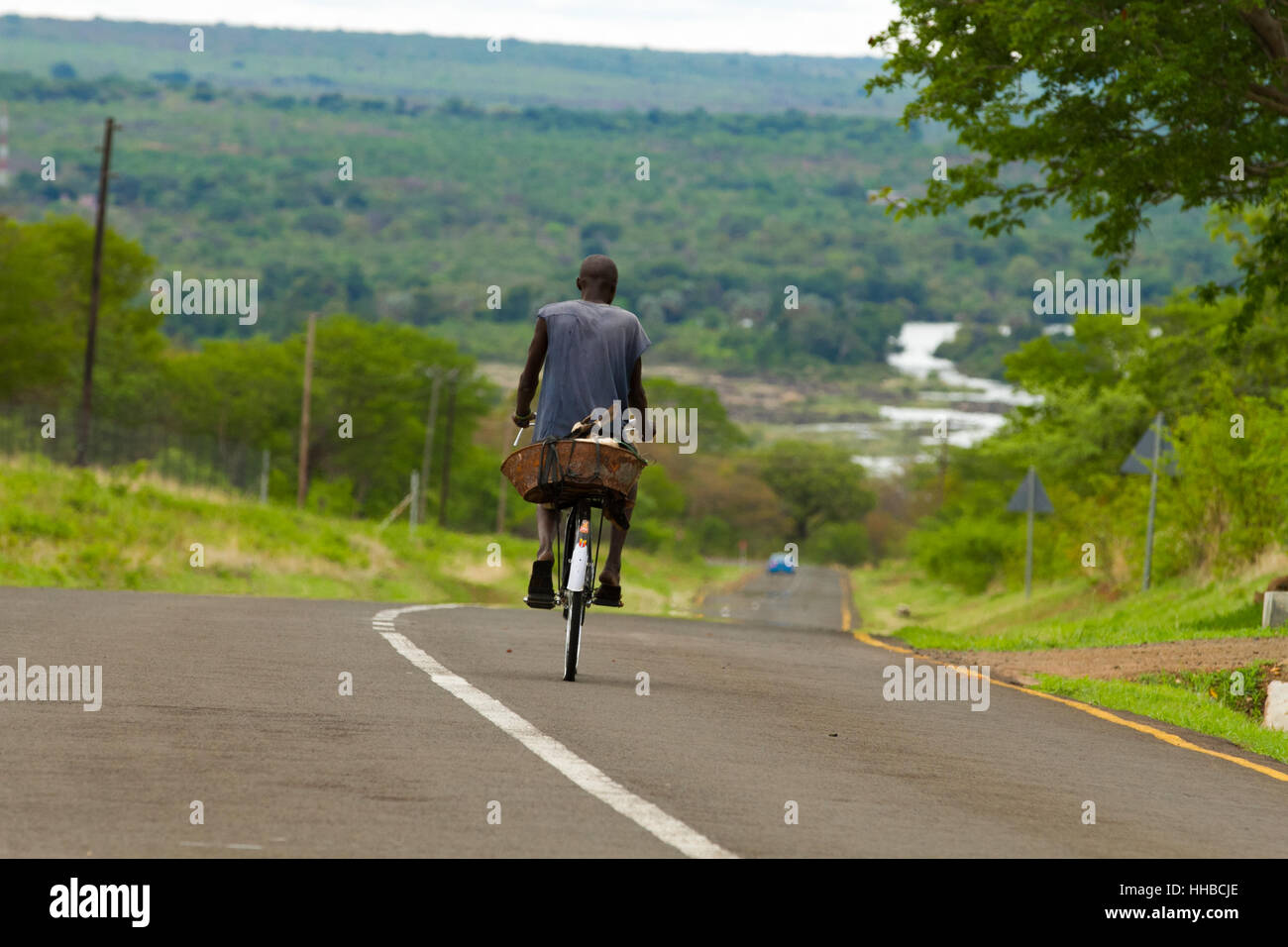 Mann Reiten Fahrrad mit Ziege mit Blick auf den Sambesi in ZambiaZimbabwe Bereich Stockfoto