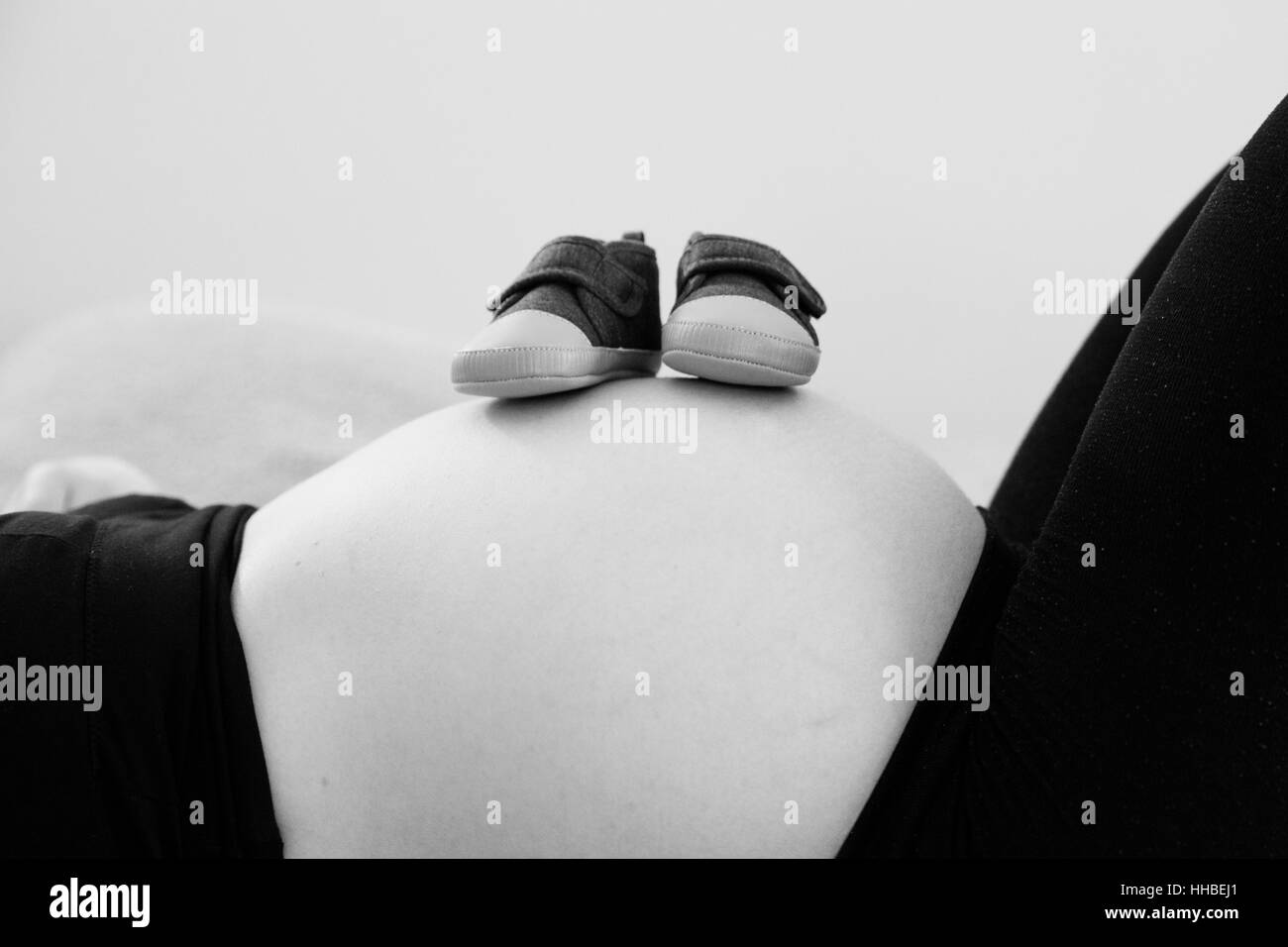 Baby-Schuhe auf den schwangeren Bauch Stockfoto