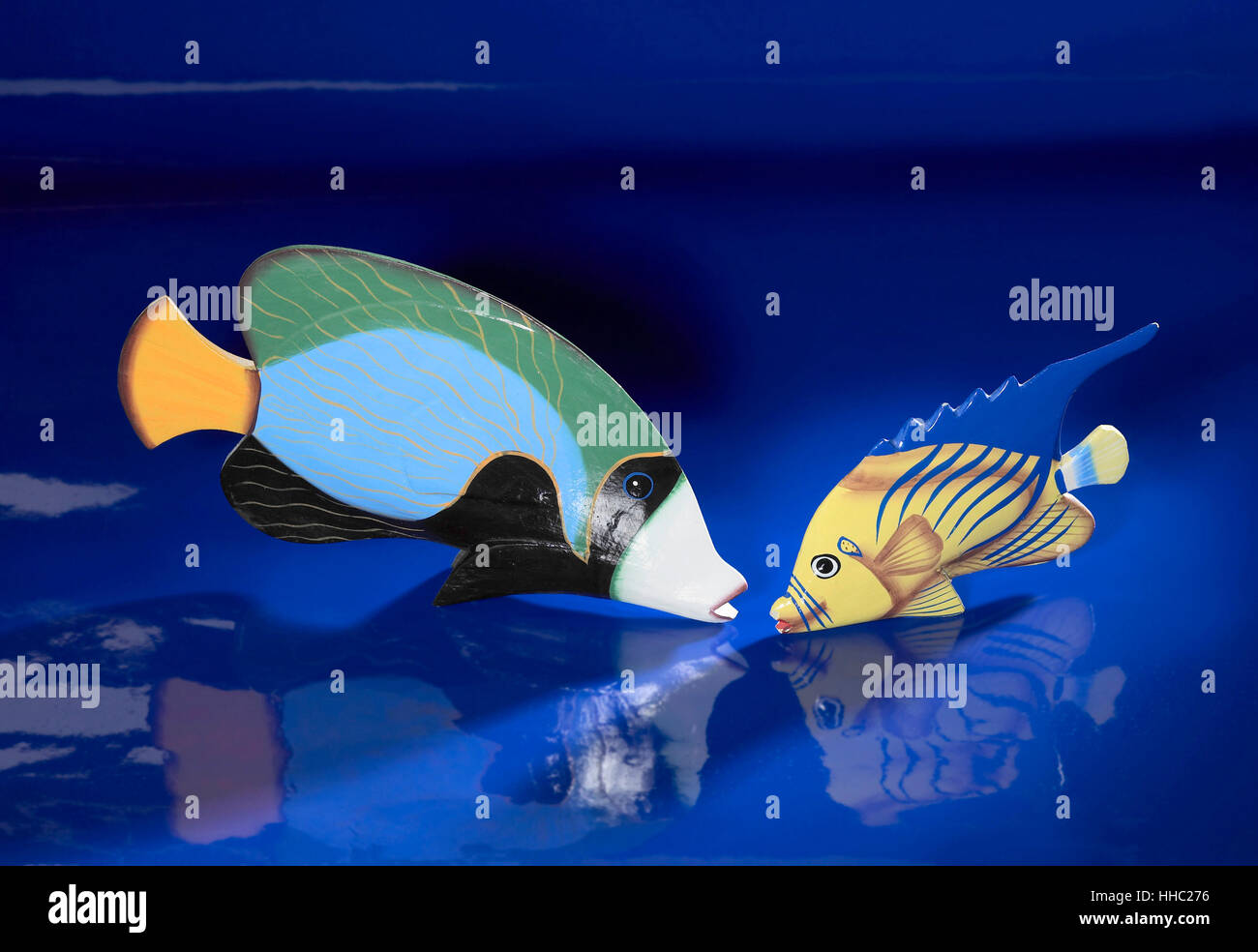 zwei hölzerne Deko Fische in blaue reflektierende Rückseite Stockfoto