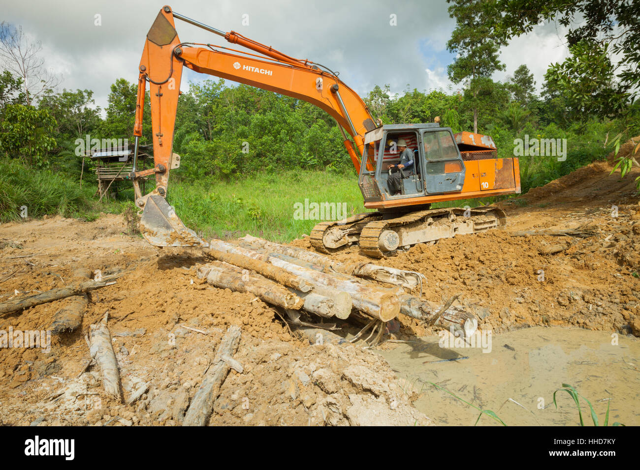 Mechanischen Bagger- oder JCB - Gebäude ein Protokoll Brücke über einem Bachbett, ländlichen Sabah, Malaysia Borneo Stockfoto