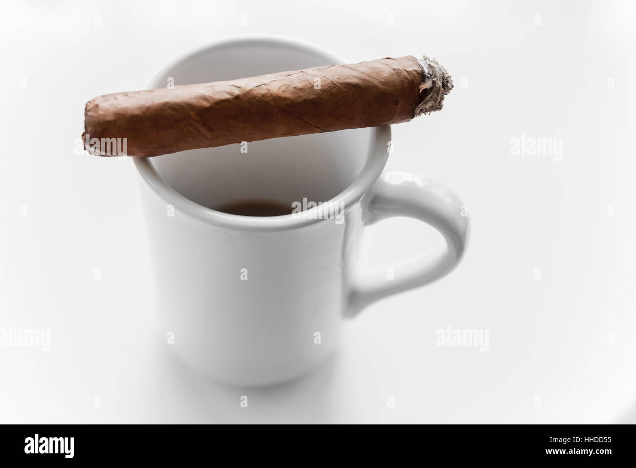 Handgemachte Zigarre legt auf weiße Kaffeetasse, Nahaufnahme Foto mit selektiven Fokus auf weißem Hintergrund Stockfoto