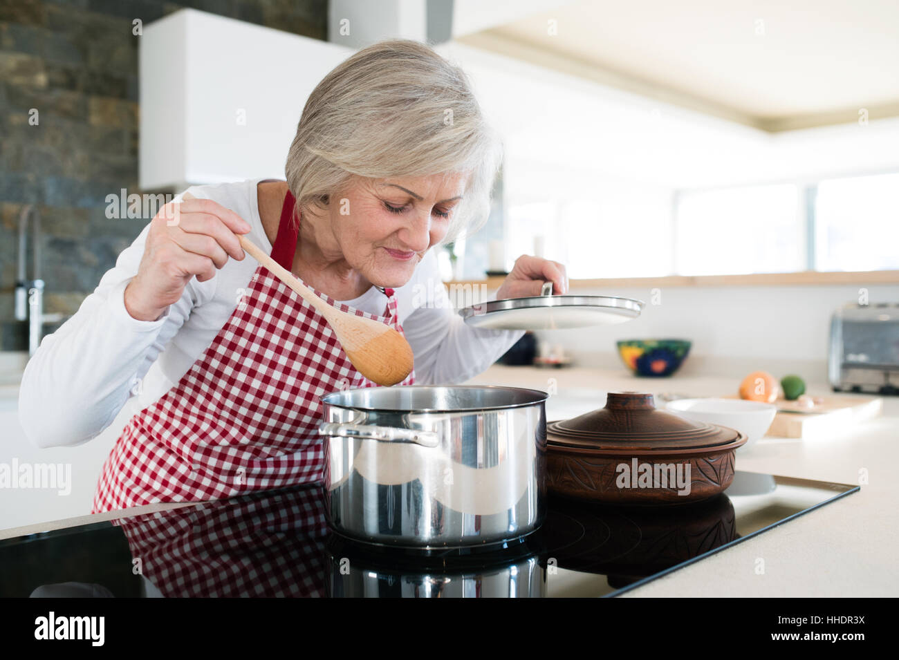 Ältere Frau in der Küche kochen, Essen in einem Topf mischen. Stockfoto