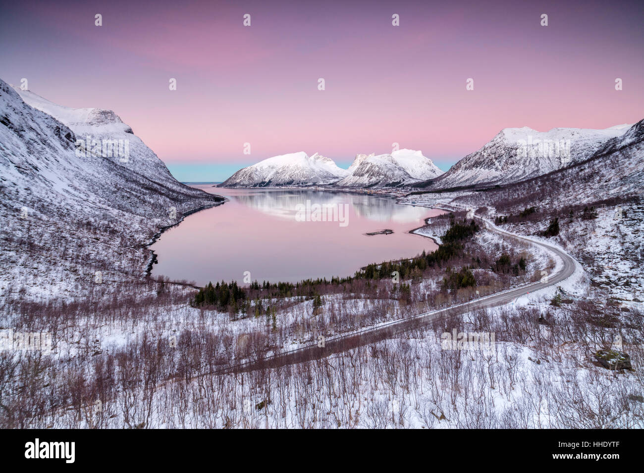 Rosa Himmel bei Sonnenaufgang leuchtet auf den schneebedeckten Gipfeln spiegelt sich in den kalten See, Bergsbotn, Senja, Troms Grafschaft, Norwegen Stockfoto
