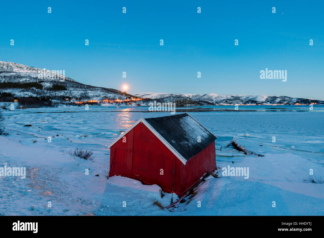 Das blaue Licht der Dämmerung über das typische Haus Fischer umrahmt das gefrorene Meer, Fjordbotn, Senja, Troms Grafschaft, Norwegen Stockfoto