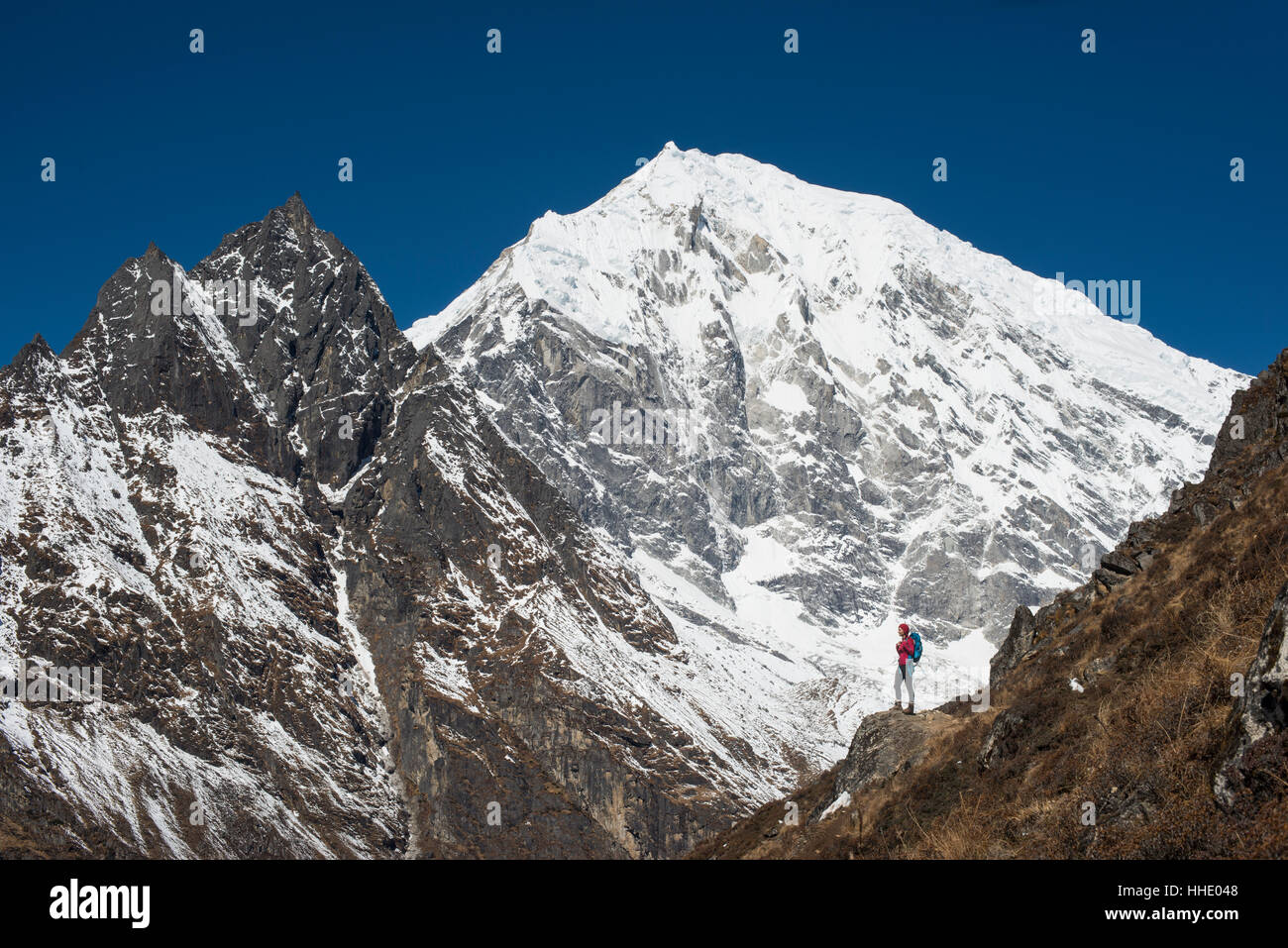 Eine Frau, die sich Kyanjin Ri im Langtang-Tal mit Blick auf Langtang Lirung in der Ferne, Langtang Region, Nepal trekking Stockfoto