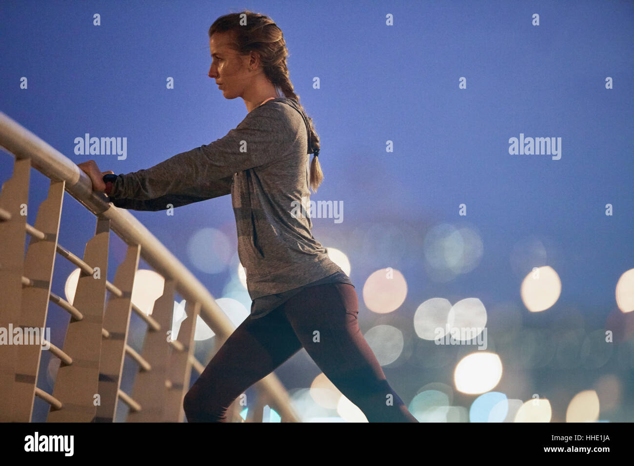 Bestimmt weibliche Läufer dehnen Beine am Steg in der Morgendämmerung Stockfoto