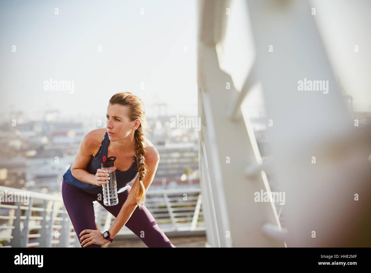Weibliche Läufer Dehnung Bein und Trinkwasser auf sonnigen urban Steg ruht Stockfoto
