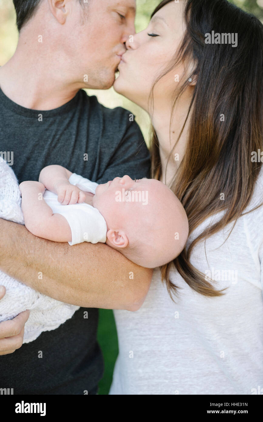 Eltern halten ein kleines Baby und küssen, ein Gruppenbild. Stockfoto
