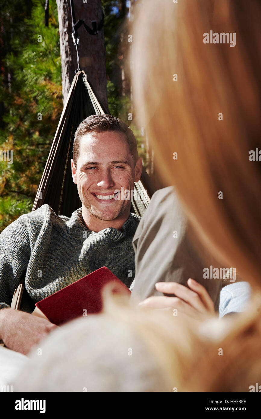 Zwei Menschen sitzen in Hängematten im Freien. Ein Mann, der lächelte eines Begleiters. Stockfoto