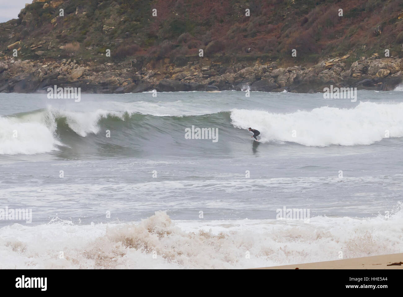 Ein Surfer Wellen in Donostia Strand (Donostia, Guipuzcoa, Baskenland, Spanien). Stockfoto