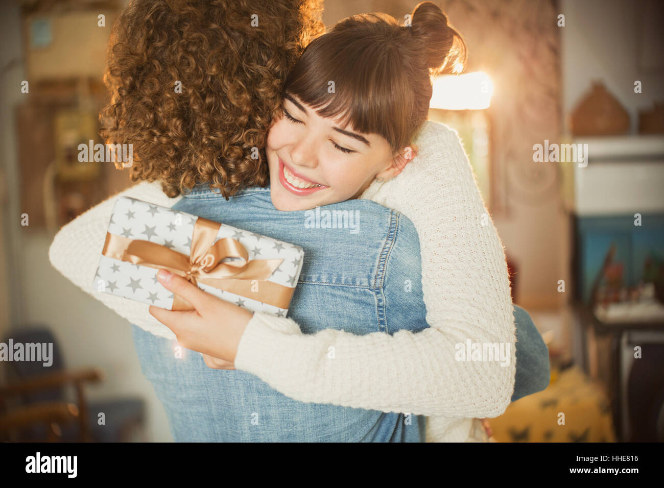 Begeisterte junge Frau umarmt Freund halten Geburtstagsgeschenk Stockfoto