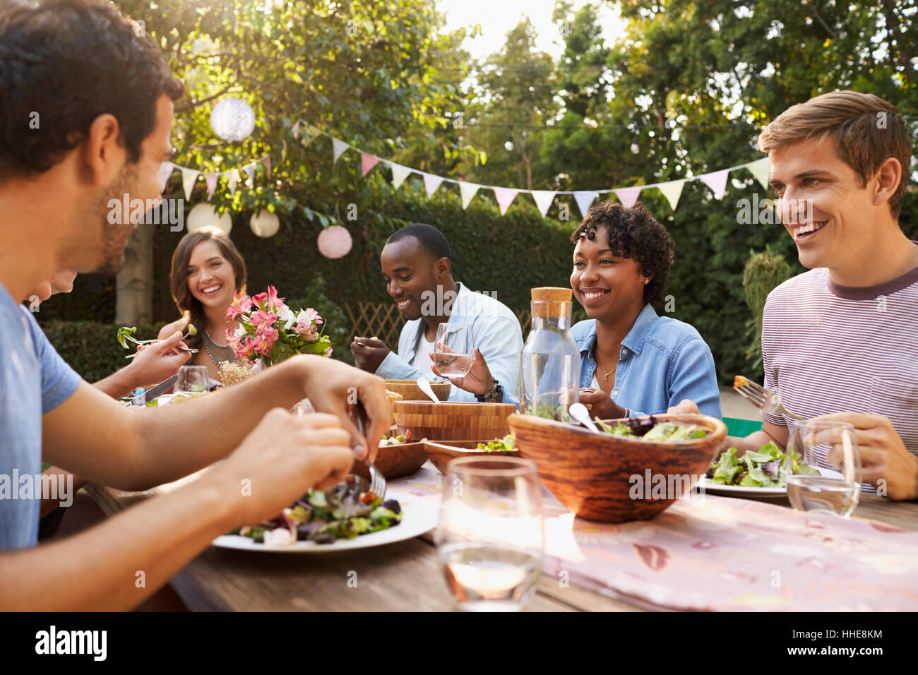 Freunde, Essen und trinken rund um Tisch auf Outdoor-Party Stockfoto