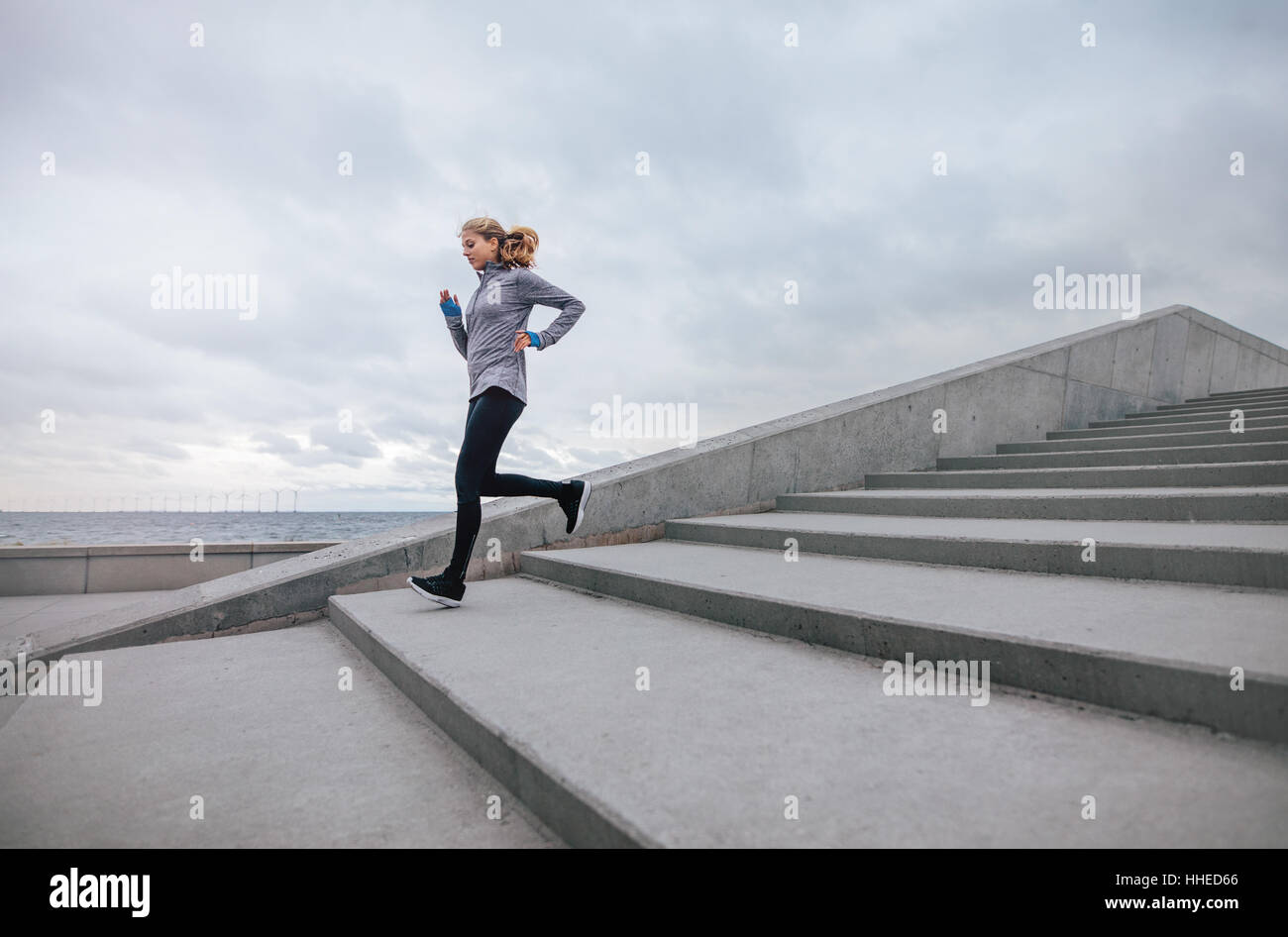Volle Länge einer gesunden Sportfrau, die die Treppe hinunter läuft. Fitnesstraining für Frauen im Freien. Stockfoto