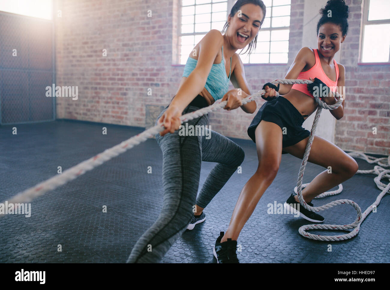 Aufnahme von zwei jungen Frauen, die Übungen mit Seil in einem Fitnessstudio. Fitness Frauen ziehen Seil im Fitnessstudio. Stockfoto