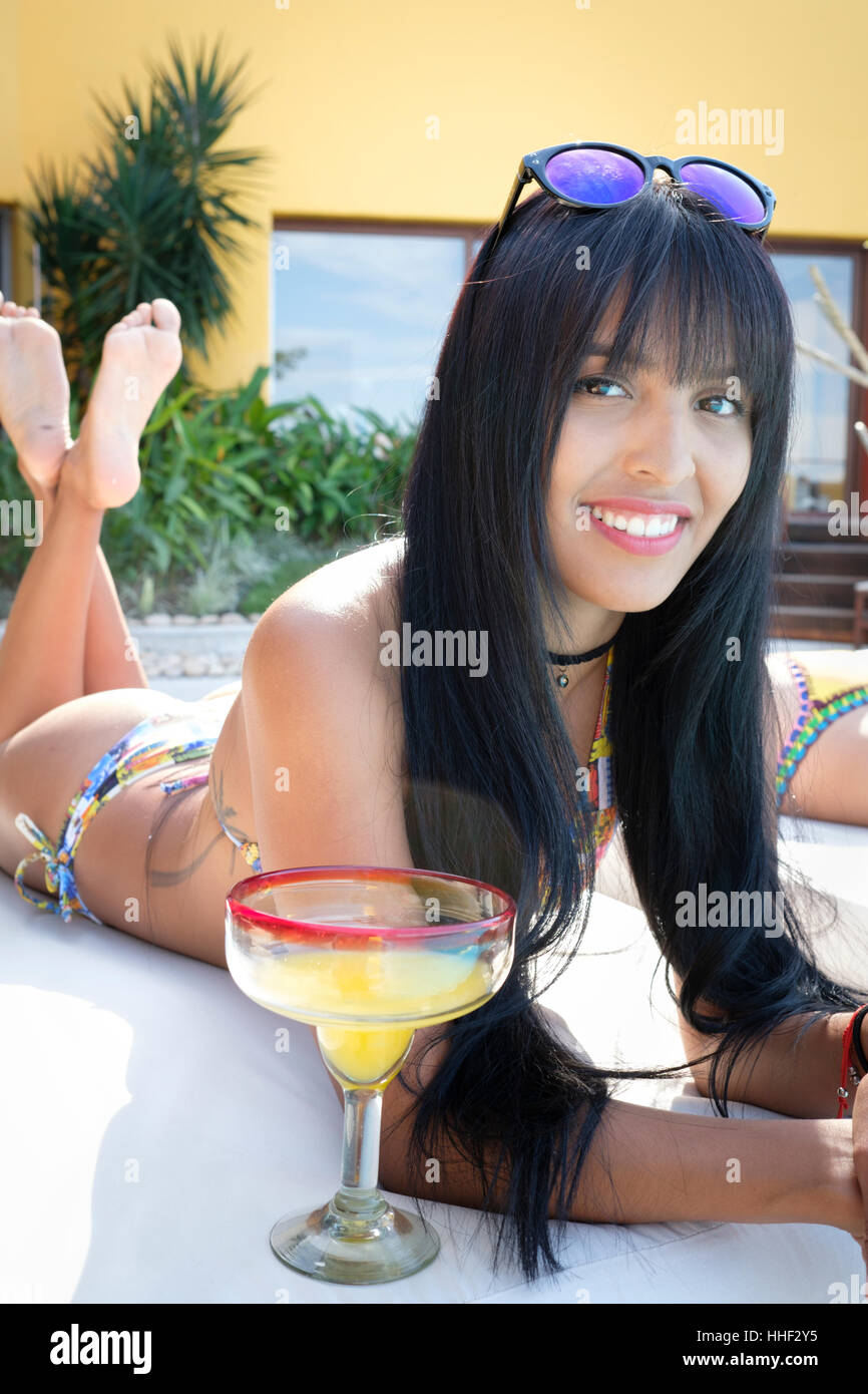 Nahaufnahme eines sehr attraktive junge lateinamerikanische Frau im Bikini beim Bräunen und genießen einen Cocktail in die Kamera Lächeln Stockfoto