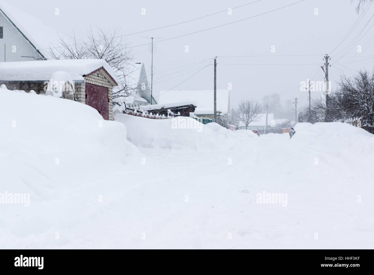 Dorfstraße im Winter mit fallendem Schnee Stockfoto