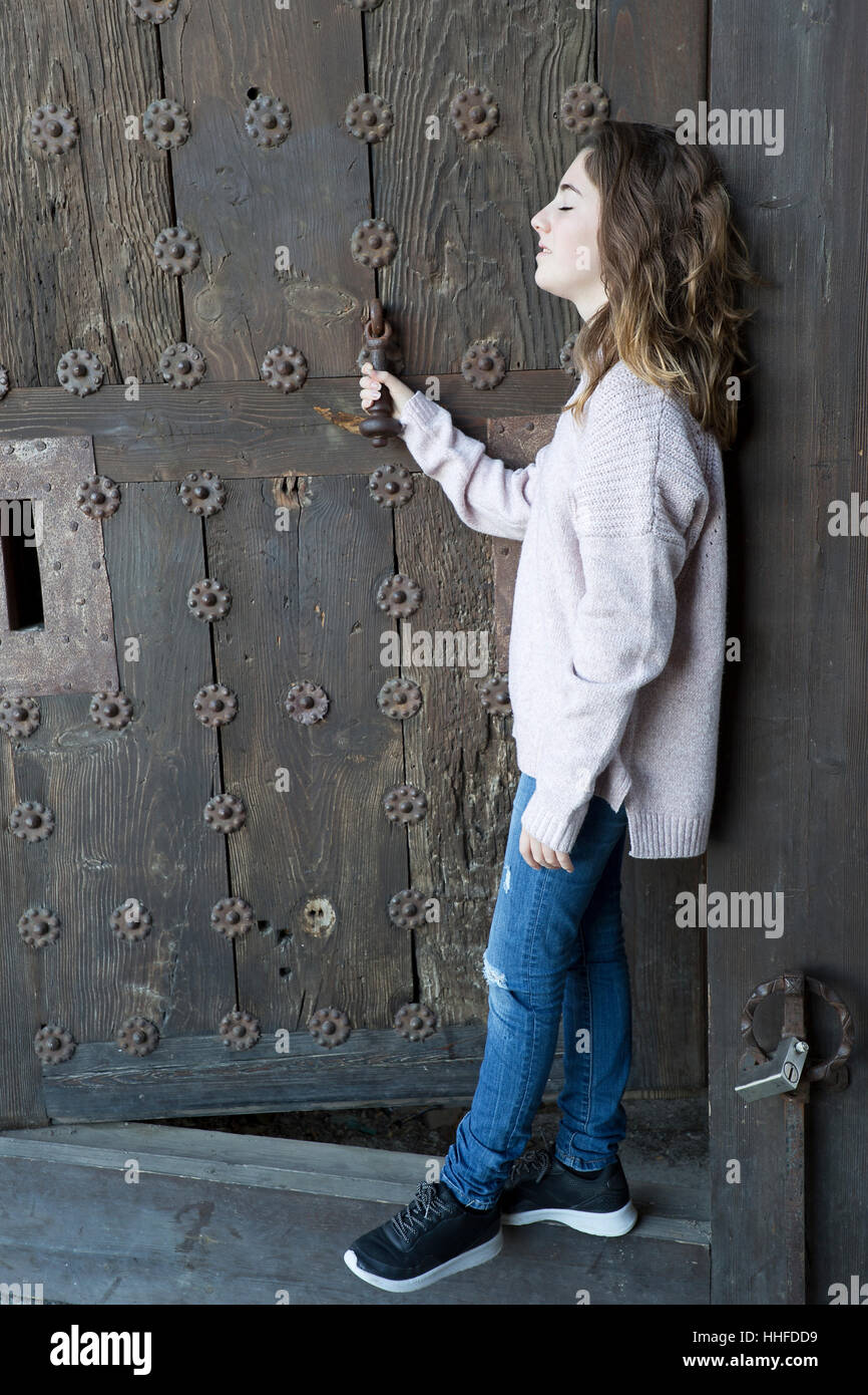 Mädchen im Profil auf einem Hintergrund von einer alten Tür. Horizontalen Schuss mit natürlichem Licht. Stockfoto