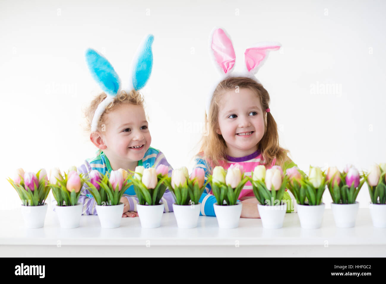 Glückliche Kinder feiern Ostern zu Hause. Jungen und Mädchen tragen Hasenohren genießen Ei jagen. Kinder spielen mit Farbe Eiern Stockfoto