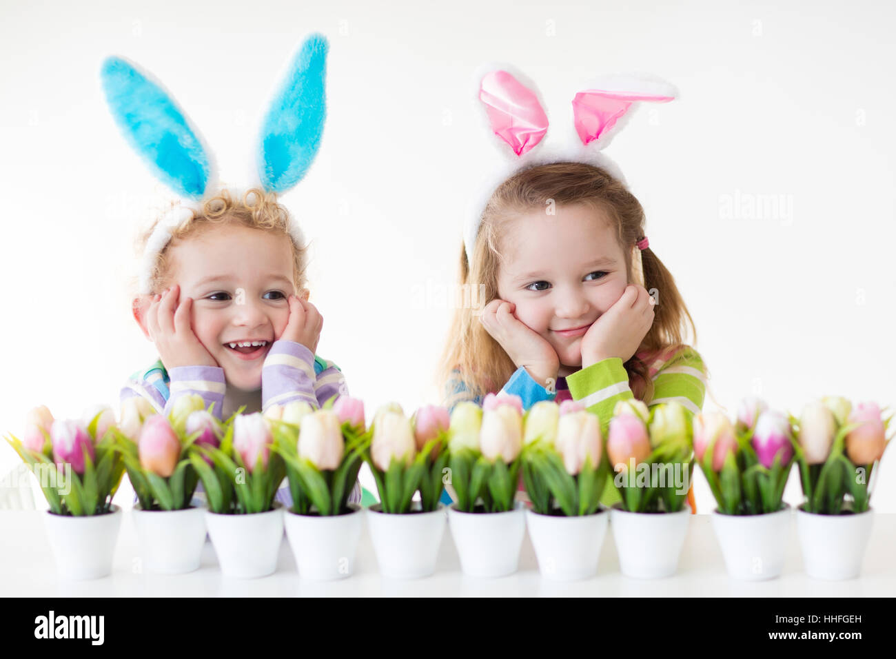 Glückliche Kinder feiern Ostern zu Hause. Jungen und Mädchen tragen Hasenohren genießen Ei jagen. Kinder spielen mit Farbe Eiern Stockfoto