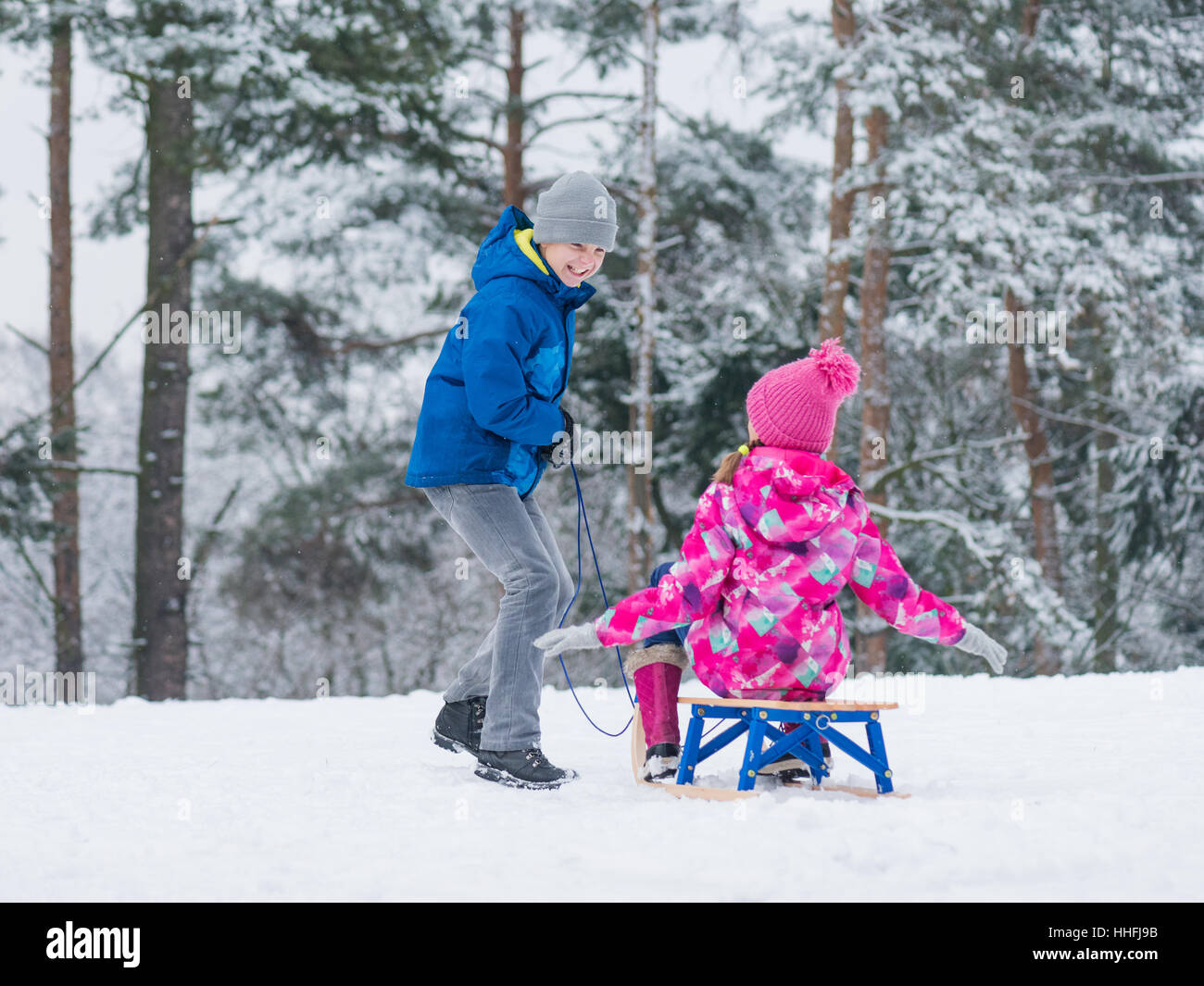 Kinder spielen im Schnee mit Schlitten Stockfoto