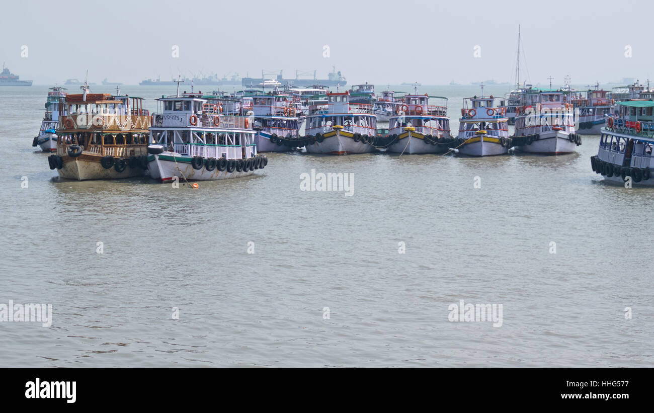 Passagierfähren im arabischen Meer vor dem Hintergrund der kommerziellen Schifffahrt in den geschäftigen indischen Hafen festgemacht Stockfoto