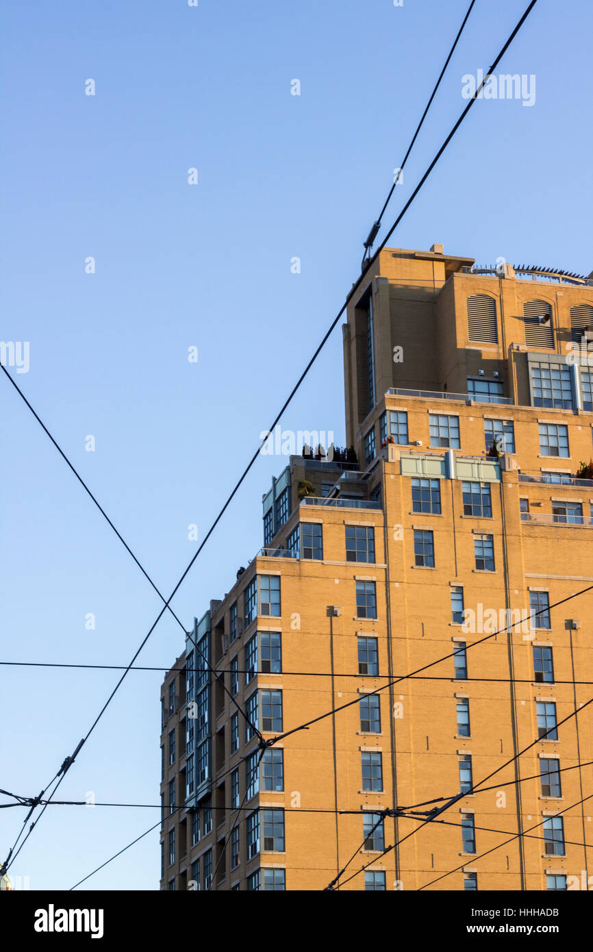 Gelbes Gebäude mit Straßenbahn Kabel vor blauem Himmel in Toronto, Ontario Stockfoto
