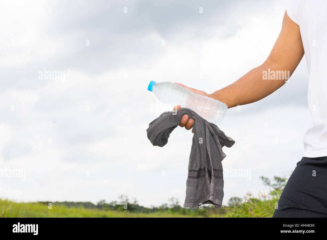 Mann mit Wasserflasche und Handtuch in seine Hand und Natur Hintergrundansicht. Stockfoto