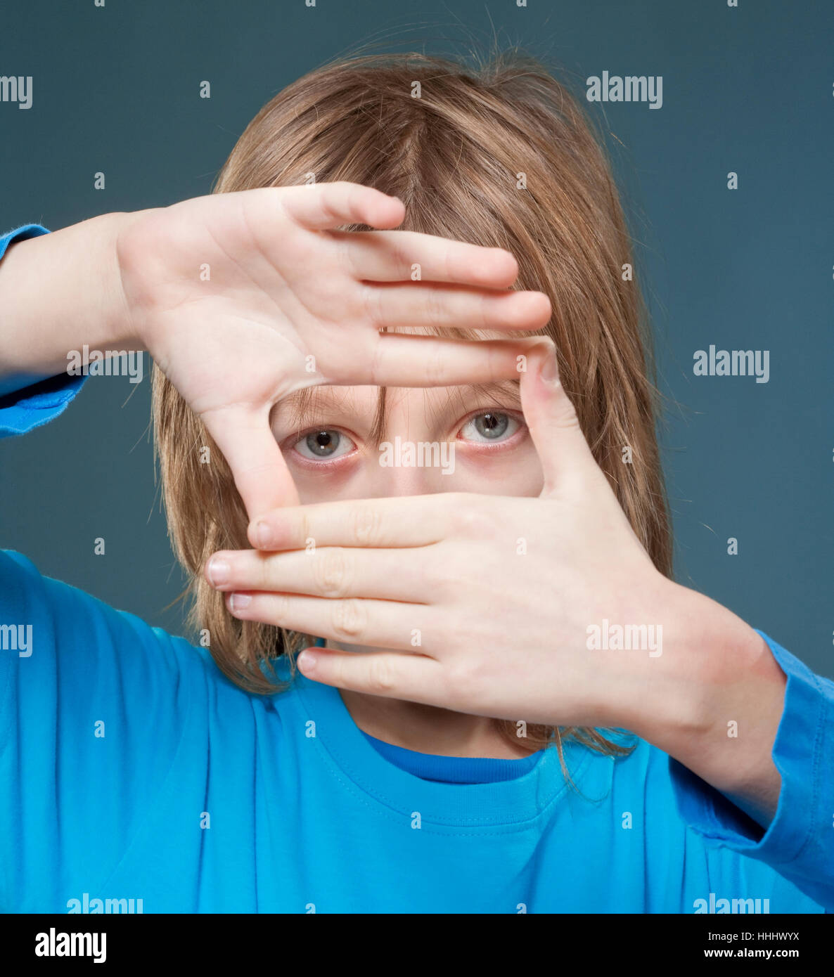 lBoy mit langen blonden Haare auf der Suche durch ein Finger Rahmen Stockfoto