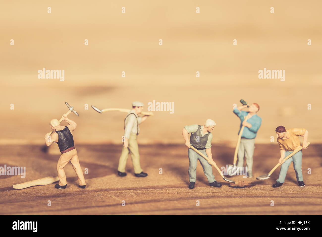 Miniatur Arbeitskraft Menschen schwer Teamarbeit auf Arbeit graben Loch auf Holz Hintergrund Vintage Farbton für Postkarte. Stockfoto