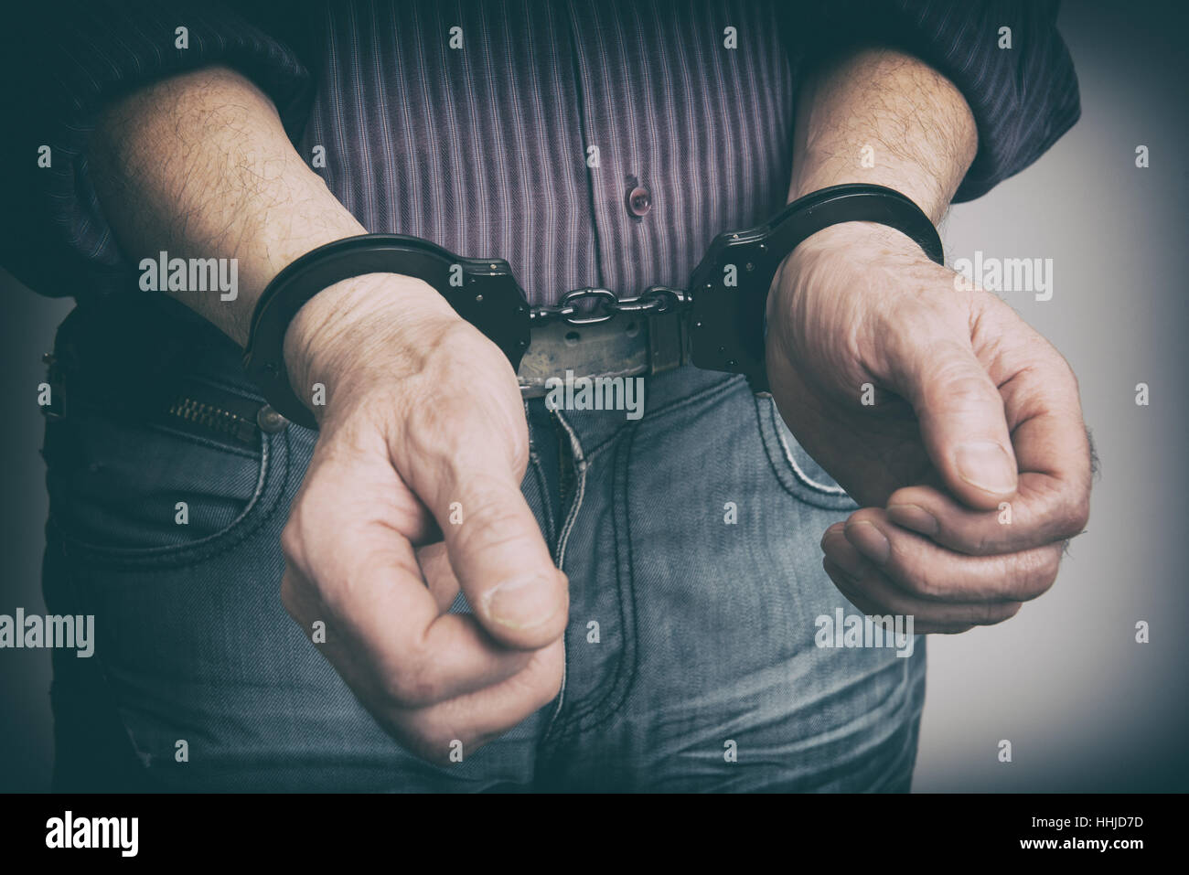 männliche Hände mit Handschellen gefesselt Nahaufnahme. Kriminalität-Konzept Stockfoto