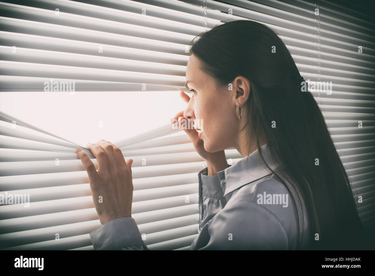 junge Geschäftsfrau aus einem Fenster zu schauen Stockfoto