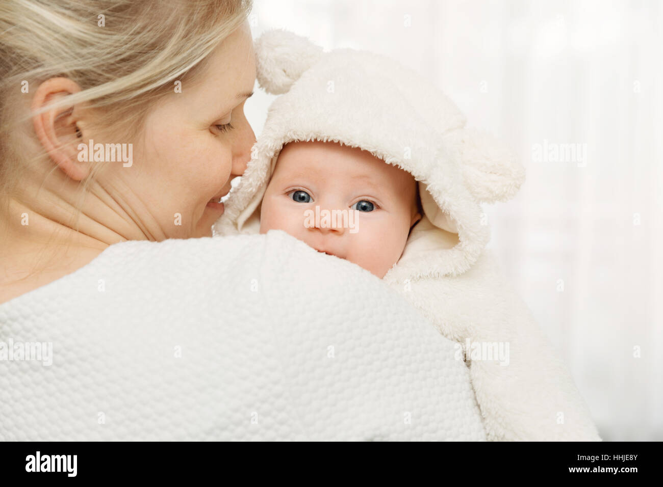 glückliche Mutter mit Säugling Babymädchen in weißen flauschigen Kostüm gekleidet Stockfoto